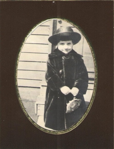 Child in hat and coat holding purse