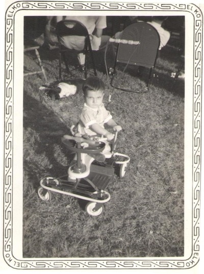 Baby boy seated on tricycle outdoors