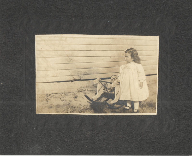 Young girl in gown standing next to rocking horse