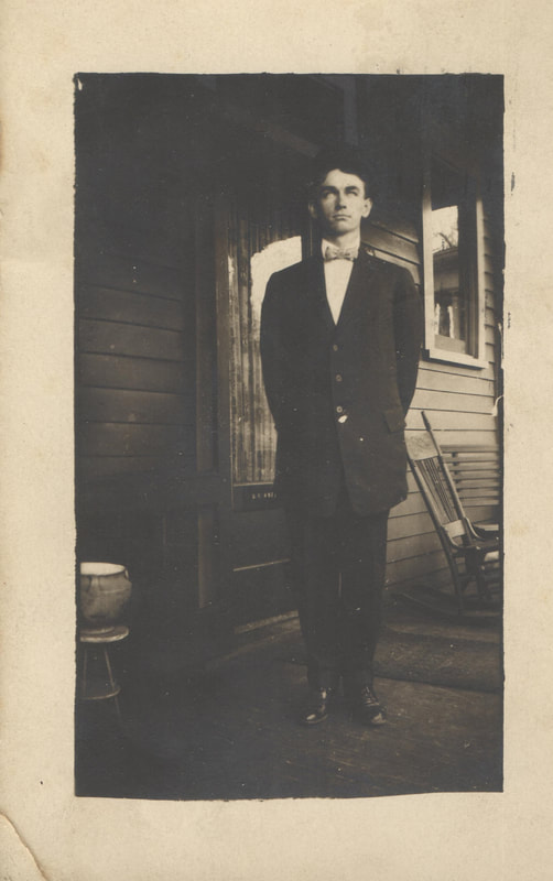 Young man in bow-tie and suit standing on porch