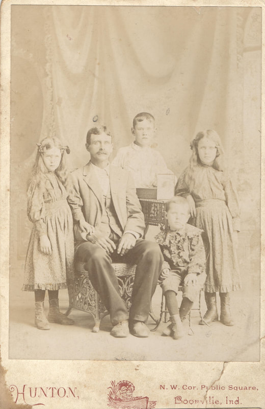 Father seated surrounded by four children