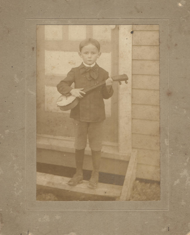 Young boy standing on step holding banjo