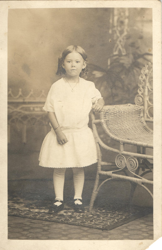 Young girl standing next to chair