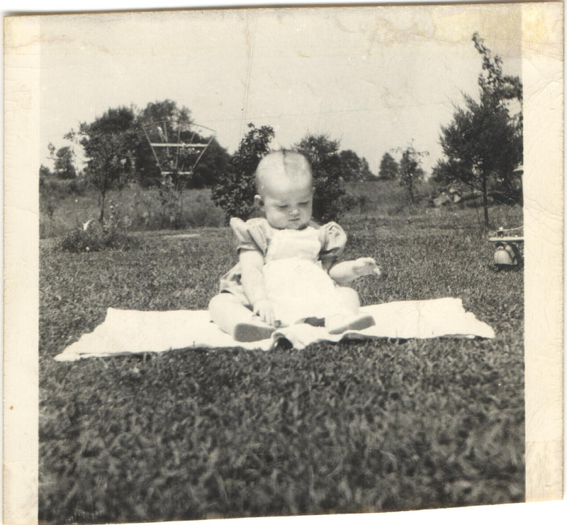 Young girl sitting on blanket in yard