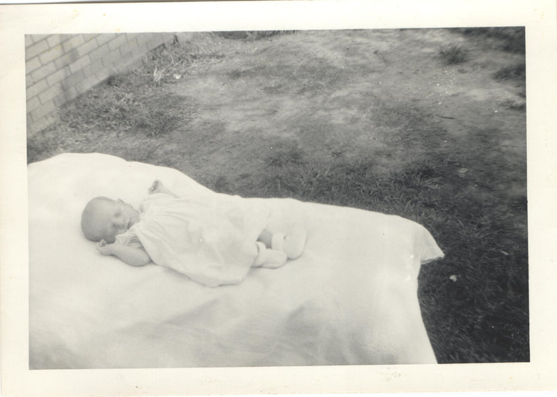 Baby girl sleeping on blanket outdoors