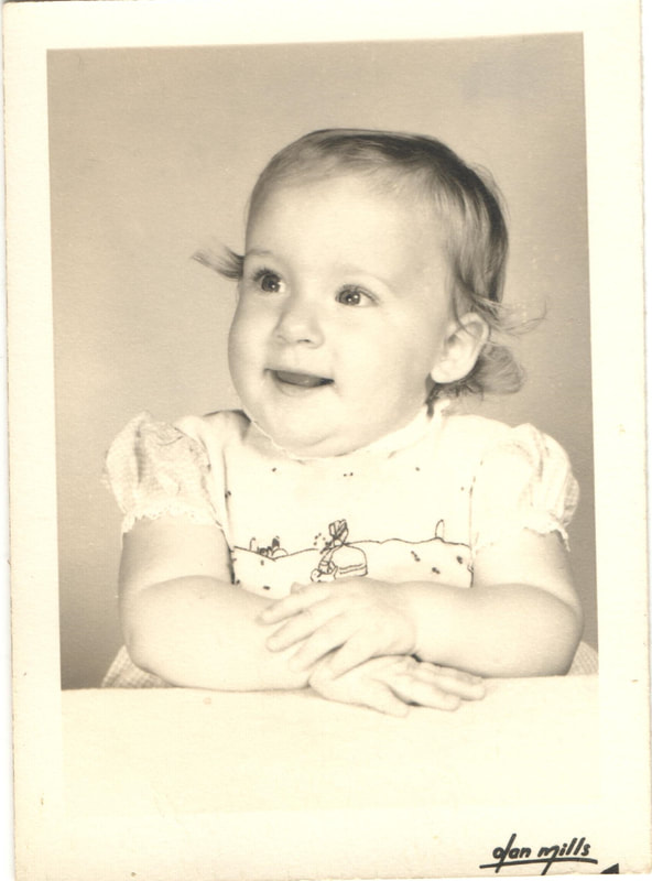 Baby girl seated with hands folded