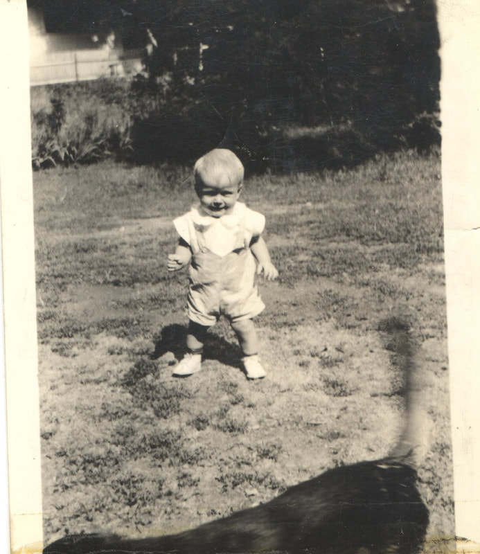 Young boy in overalls standing in yard