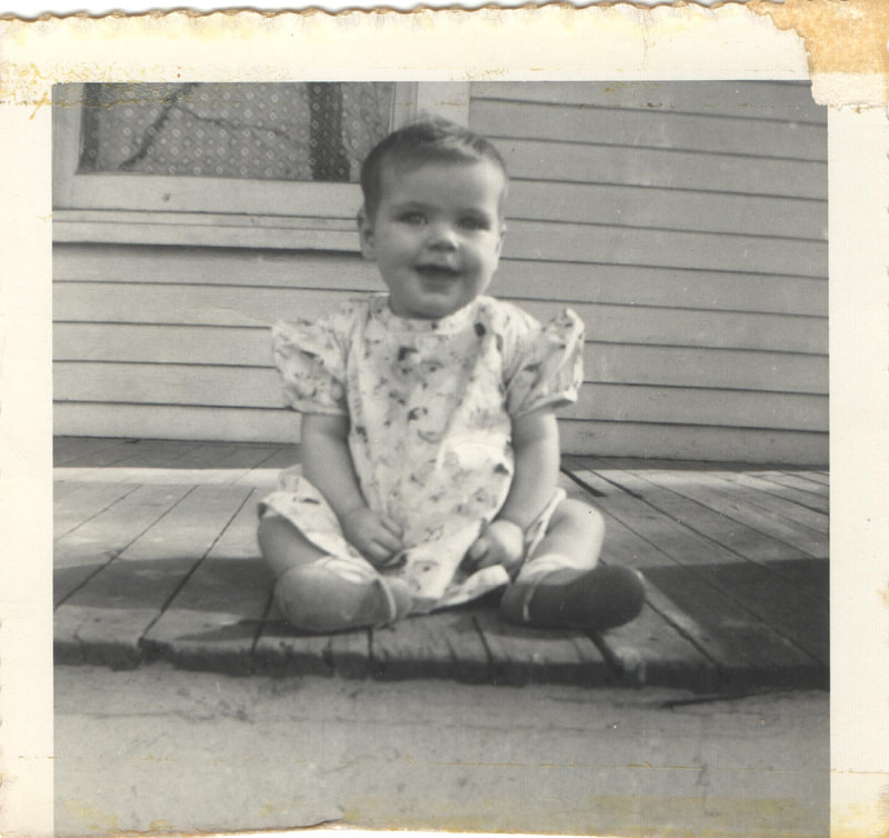 Baby girl sitting on porch of home