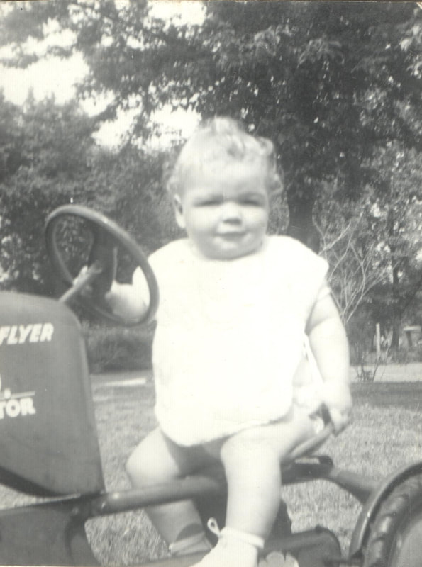 Baby girl seated on toy tricycle