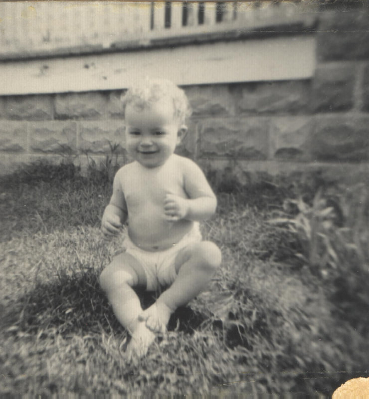 Baby boy in diaper seated on lawn 