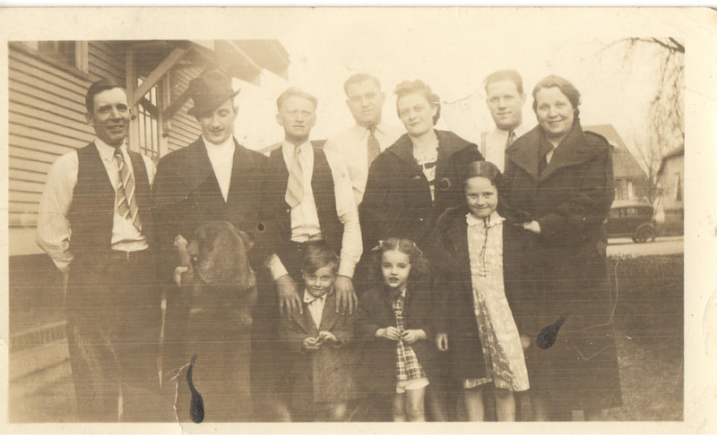 Family standing next to house in dress clothes