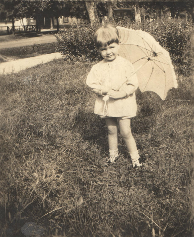 Young girl holding umbrella in yard
