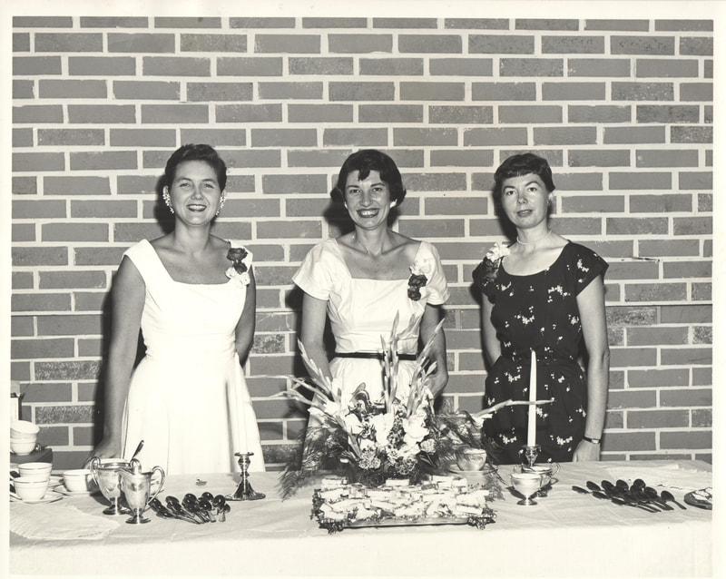 Three women standing at formal dining setting