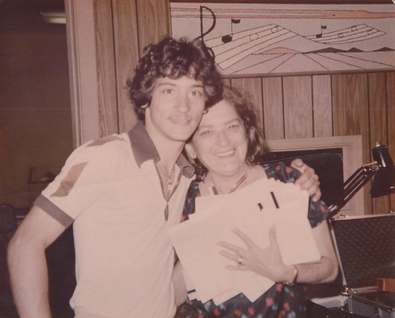Man with mustache in polo shirt embracing woman holding papers at recording studio