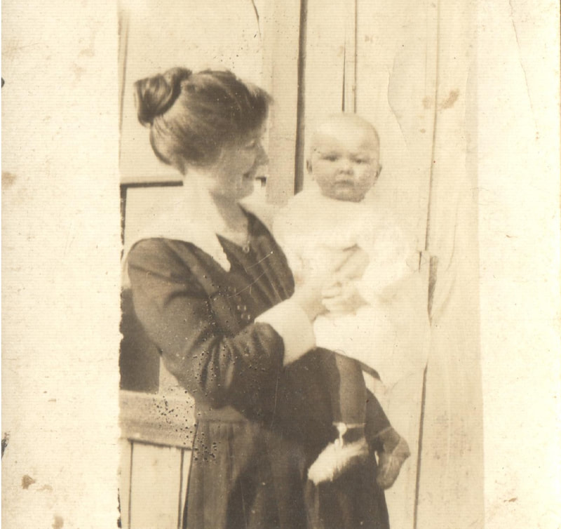 Woman with hair in bun holding baby in gown