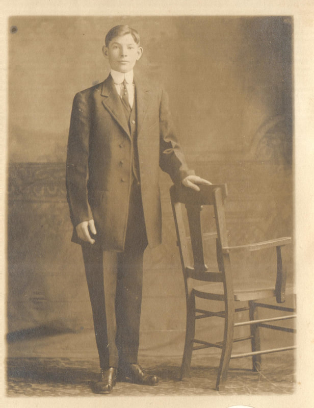 Young man in suit standing next to chair