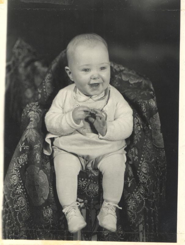 Baby boy seated with hands together