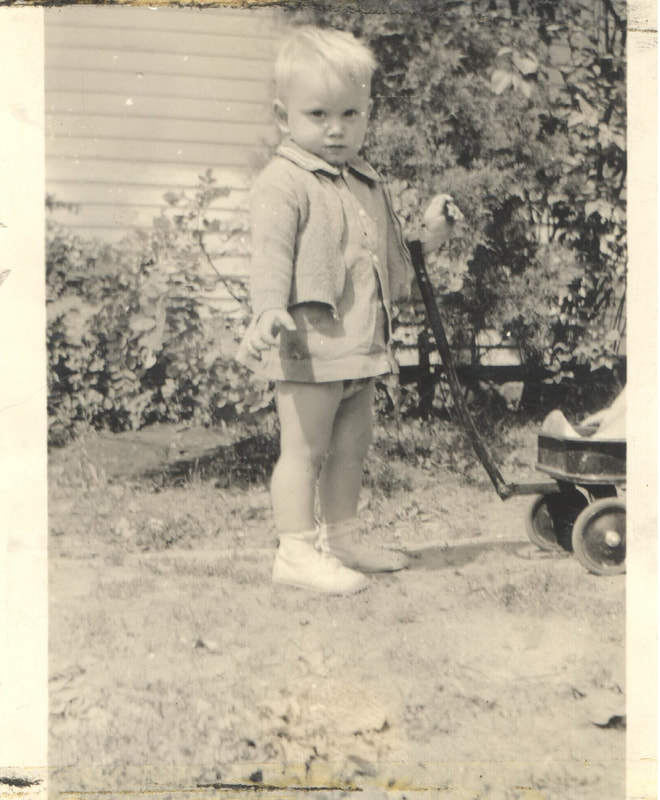 Young boy with blond hair holding onto toy wagon