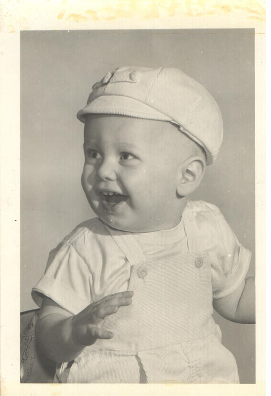 Smiling baby boy in cap and overalls