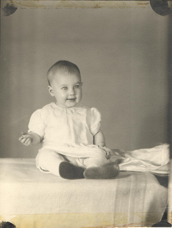 Baby girl seated on bed