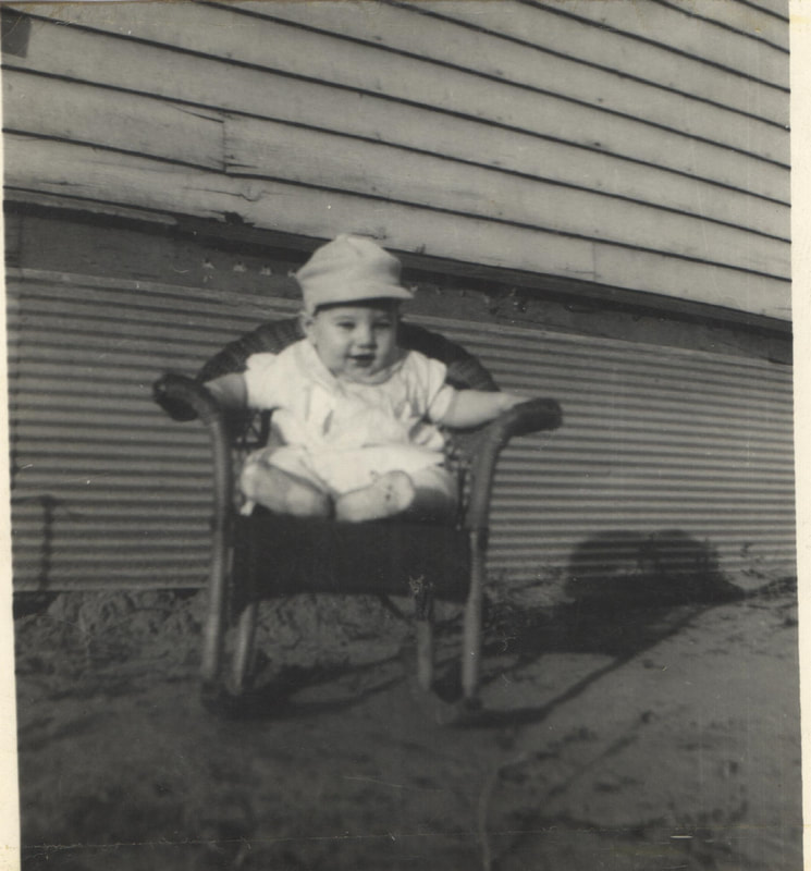 Baby boy with hat seated in chair