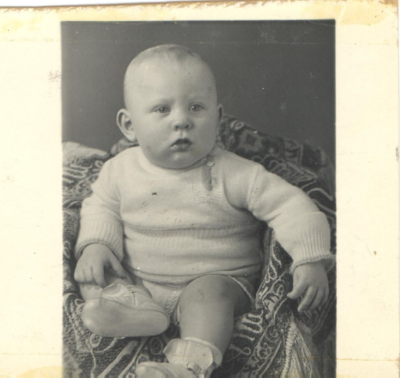 Baby boy in sweater seated on chair