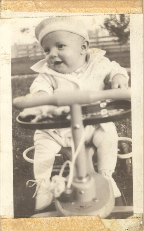 Baby boy in beret riding toy bike