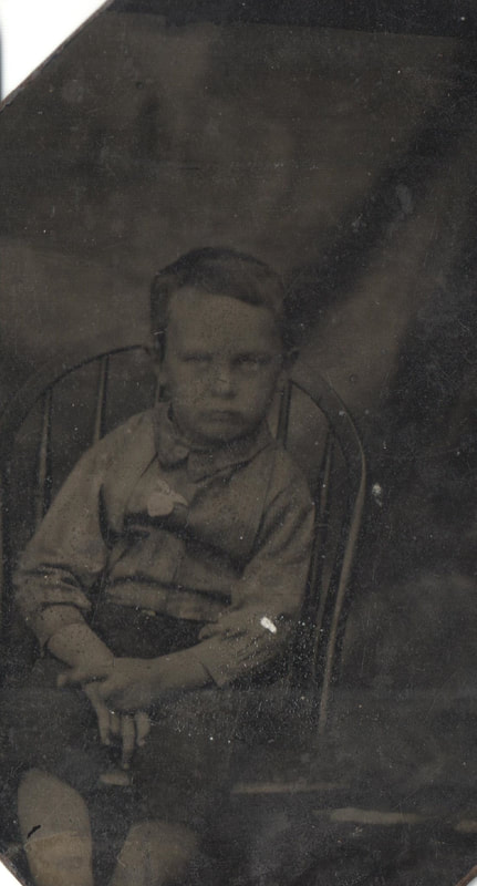 Young boy sitting in a chair with hands folded