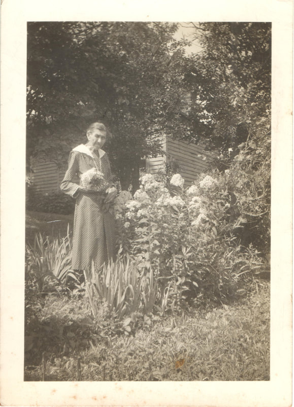 Elderly woman standing in flower garden
