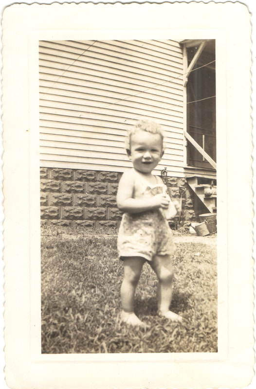 Toddler in overalls standing in yard