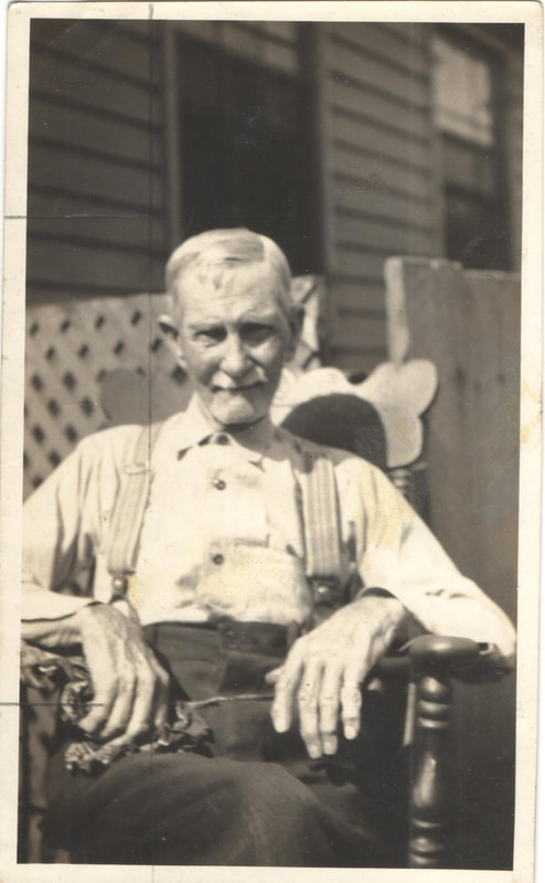 Elderly man in suspenders seated in chair