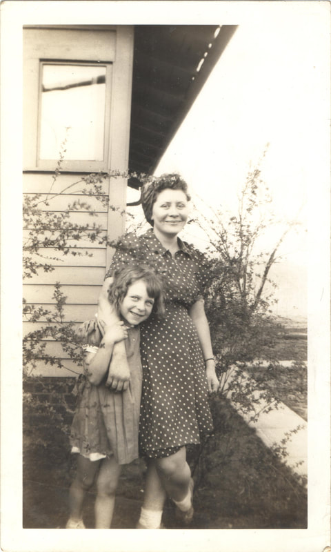 woman and young girl standing together in yard