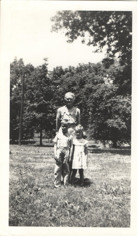 Elderly woman standing with young children outdoors