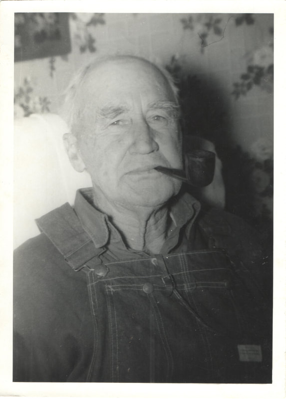 Elderly man in overalls smoking pipe