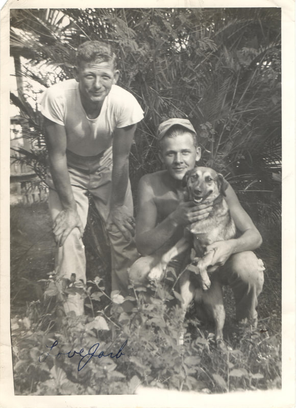 Soldier holding dog next to soldier standing