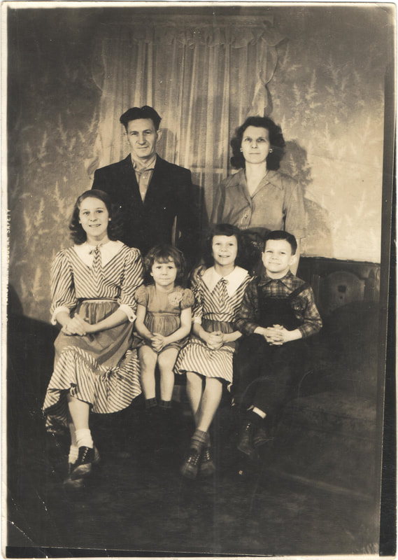 Man and woman standing behind seated children