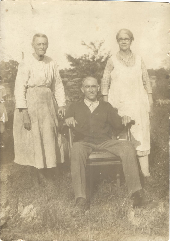 Elderly women standing behind seated elderly man