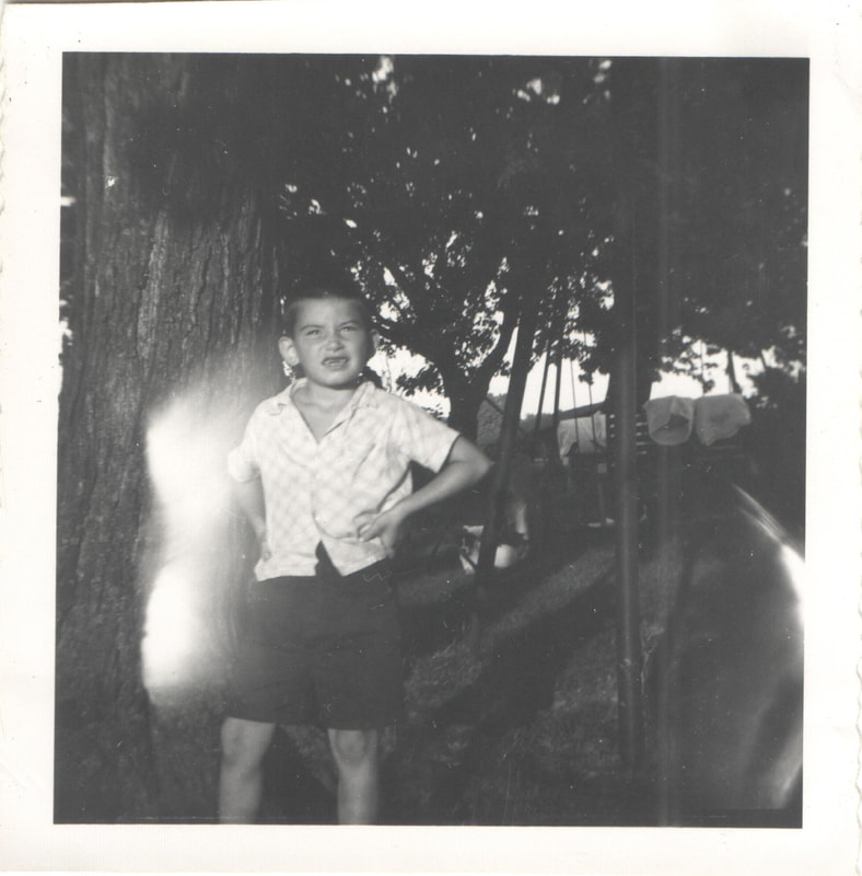 Young boy standing with hands on hips next to swing-set