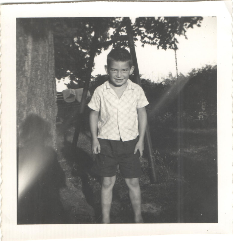 Young boy standing next to swing-set