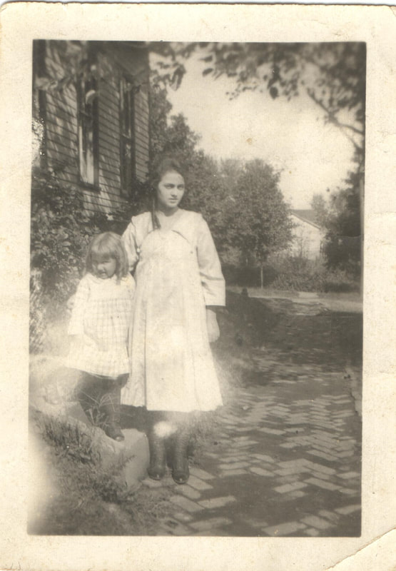 Young woman standing on brick path next to young girl