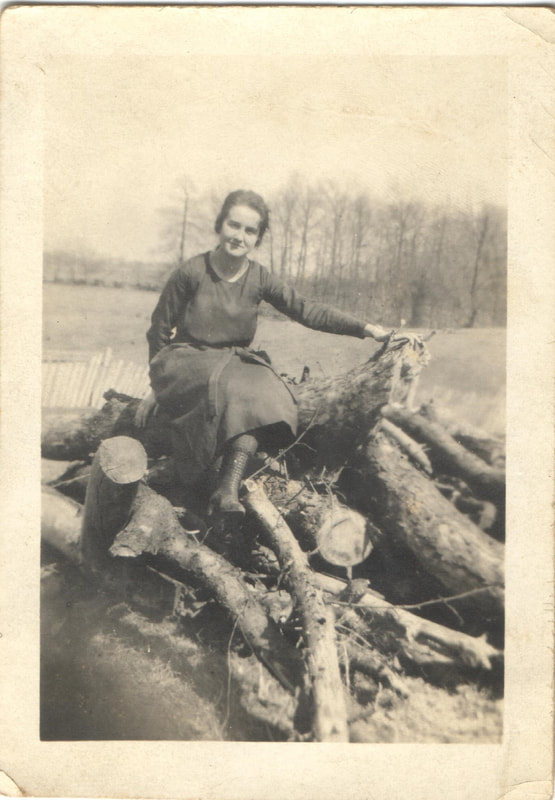 Woman seated on felled logs