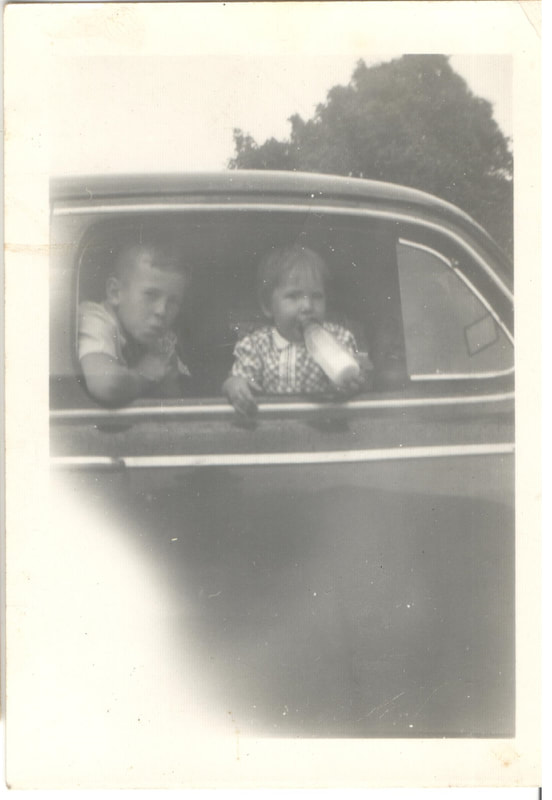 Young boy and baby girl with bottle seated in car