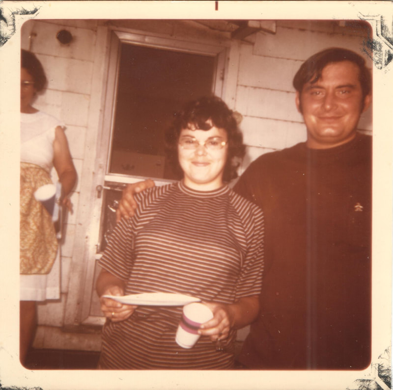 Man with arm around woman holding plate and cup