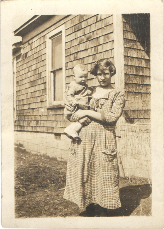 Woman holding baby in front of house