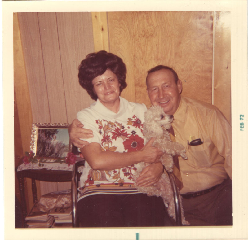 Man and woman sitting together with toy poodle dog