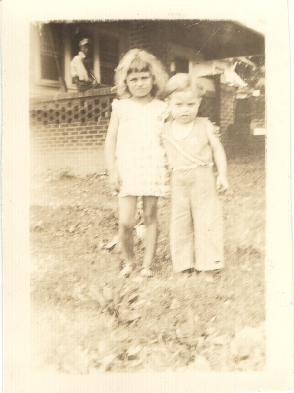 Young girl and boy standing together in front of house
