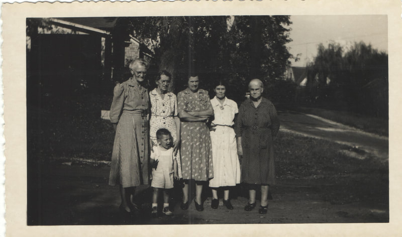 Elderly women standing behind young boy outdoors
