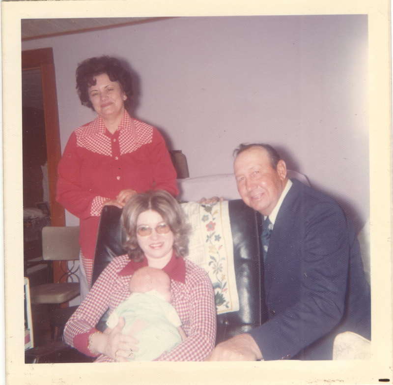 Woman holding baby surrounded by elderly couple