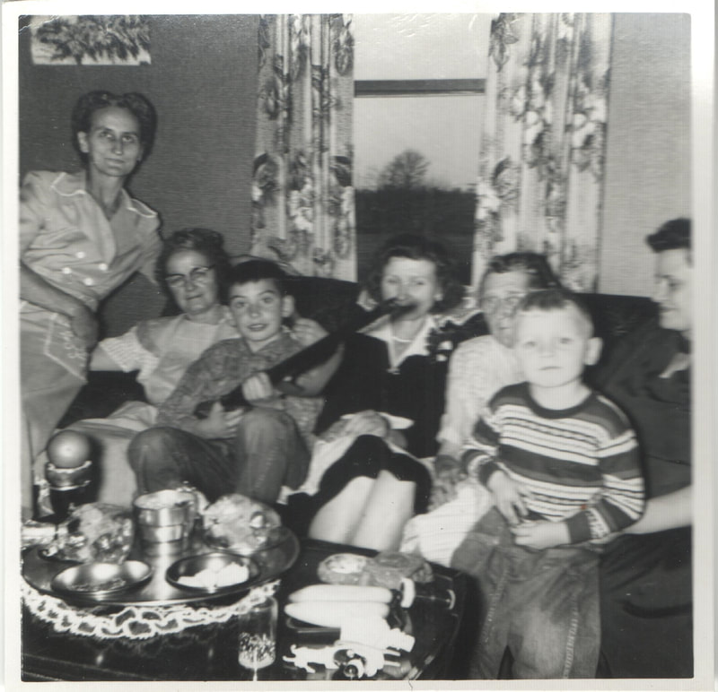 Young boy holding rifle seated with family on couch