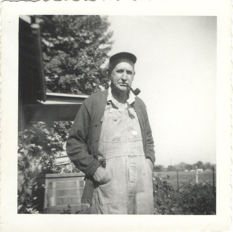 Elderly man in overalls with pipe in mouth